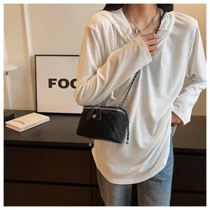 Close-up of black quilted chain box bag worn by a model in minimalist room setting