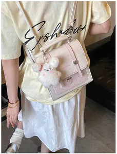 Close-up detail of a pink polka-dot satchel backpack with a white plush bunny charm