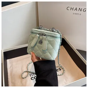 Detail of mint green quilted mini vanity bag featuring a stylish silver chain strap