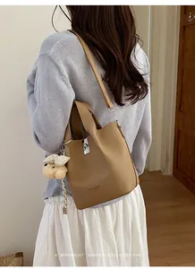 Achteraanzicht van een vrouw met een beige leren emmertas en een pluchen bedel