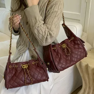 Close-up of burgundy quilted shoulder bag with gold chain and interlocking hardware detail