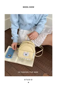 Close-up of a cute yellow cartoon bear backpack styled with a blue smartphone and book.