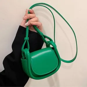 Close-up detail of a vibrant green mini crossbody bag with a modern curved design