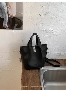 Detail van een zwarte kiezellederen emmertas op een prachtig vintage houten oppervlakte.