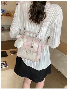 Back view of a pink polka dot backpack with strawberry charm and rabbit pendant