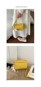 Vista dettagliata di una borsa a tracolla gialla minimalista con ciondolo animale.