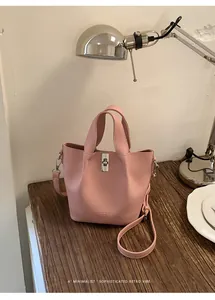 Verfijnde roze leren emmertas in een minimalistische retro lifestyle omgeving