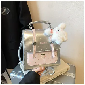Detail shot of a silver metallic mini backpack with pink polka dots and a strawberry