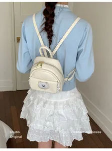Detailed back view of a stylish cream mini backpack with cartoon bear and lace trim