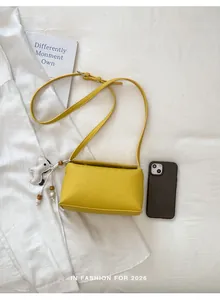 Borsa a tracolla gialla con ciondolo a cane accanto a uno smartphone per le dimensioni