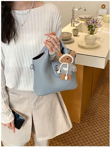 Elegante hellblaue Leder Eimertasche mit einem süßen Teddybär-Anhänger für stilvolle Damen