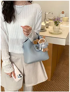 Detailansicht einer stilvollen hellblauen Eimertasche aus Leder mit Bärenanhänger