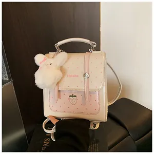 Detailed view of a cute cream polka-dot backpack with a plush bunny keychain and strawberry