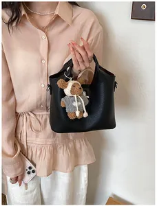 Detailansicht einer eleganten schwarzen Beuteltasche aus Leder mit süßem Bärenanhänger