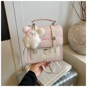 Detail view of pink polka dot backpack featuring a fluffy bunny charm and strawberry embroidery