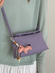 Borsa a tracolla viola in pelle martellata con un simpatico ciondolo a forma di cavallo.