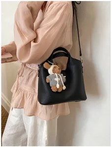 Nahaufnahme einer eleganten schwarzen Eimertasche aus Leder mit einem Bärenanhänger