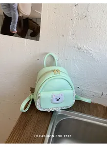 Detail of mint green mini backpack featuring cute bear patch and lace trim detail.