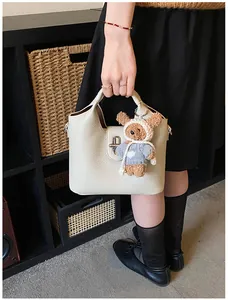 Detailansicht der eleganten beigen Leder-Beuteltasche mit süßem Plüschbären-Anhänger