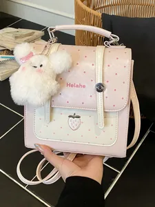 Stylish pink polka dot backpack with strawberry embroidery and a cute white plush charm.