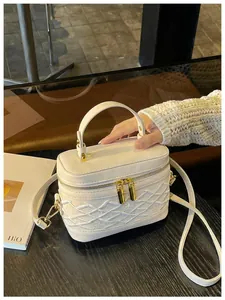 Detalle de minibolso blanco bordado con elegantes cremalleras doradas y diseño de caja estructurada
