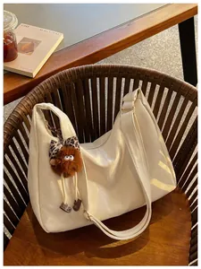 Large capacity off-white hobo shoulder bag with fuzzy brown charm on a wooden chair