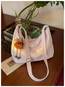 Pink large capacity shoulder bag with a cute plush monster charm in a lifestyle setting