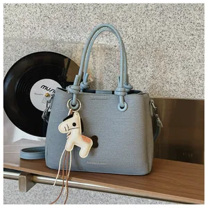 Close-up view of the textured blue bucket bag featuring a cute white horse charm
