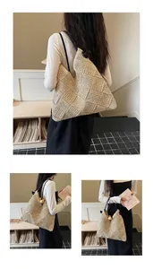 Vue détaillée d'un grand sac fourre-tout en paille tissée avec anses noires.
