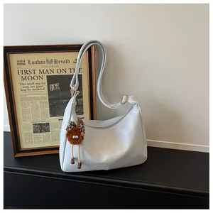 Detailed view of the white large-capacity hobo bag with adjustable strap and doll charm