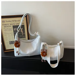 A detail shot of two cream-colored hobo bags featuring adorable plush doll charms
