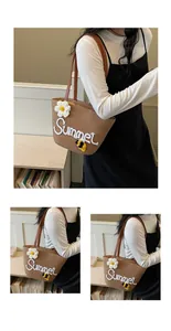 Detail view of a straw tote bag with white Summer embroidery and floral accents.