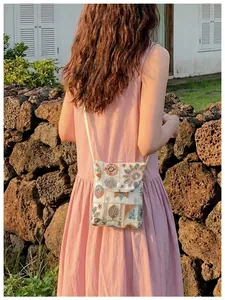 Donna di spalle con una borsa a tracolla per cellulare ricamata in un giardino