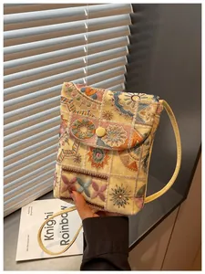 Vista dettagliata di una borsa a tracolla ricamata in stile etnico tenuta contro uno sfondo