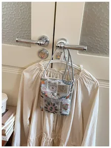 Vista dettagliata di una borsa per cellulare ricamata appesa a una camicetta beige.