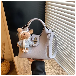 Nahaufnahme einer modischen lavendelfarbenen Leder-Eimertasche mit süßem Teddybär-Anhänger