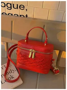 Primer plano detallado de un bolso de mano rojo bordado con doble cremallera dorada