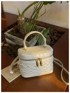 Elegante mini bolso caja blanco con detalles trenzados en un entorno de estilo de vida