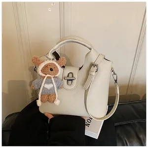 Detailansicht einer schicken cremefarbenen Leder-Beuteltasche mit süßem Bärenanhänger.