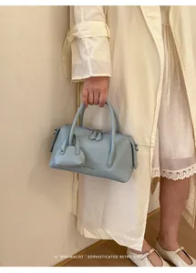 Fashionable light blue lychee grain bowling bag with matching charm held by a model