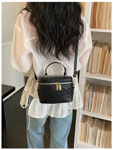 Mini bolso tipo caja negro con relieve mostrado en la espalda de la modelo