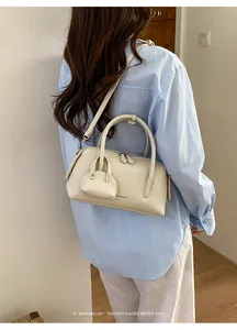 Close-up of a cream-colored litchi leather bowling bag with mini decorative pouch.
