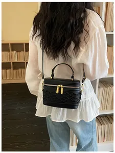 Modelo que luce un elegante bolso mini tipo caja negro con herrajes dorados en tienda