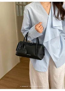 Black litchi grain leather bowling bag for women in an elegant lifestyle portrait pose