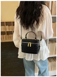 Vista trasera de un mini bolso bandolera de cuero negro con una blusa blanca clásica