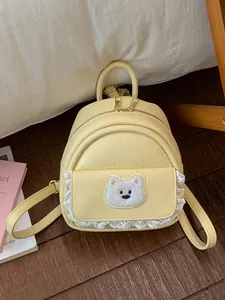 Cute yellow women's mini backpack with fluffy bear patch and white lace trim detail.