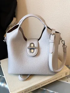Elegante Beuteltasche aus genarbtem Leder mit Griff und silbernem Drehverschluss.