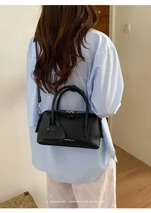 Detailed back view of a woman carrying a stylish black lychee-grain leather bowling bag