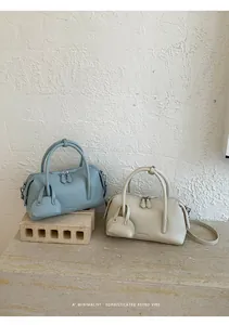 Minimalist litchi grain bowling bags in light blue and cream with matching charms