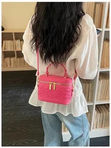 Vista trasera de un mini bolso bandolera rosa con cremalleras doradas y textura tejida